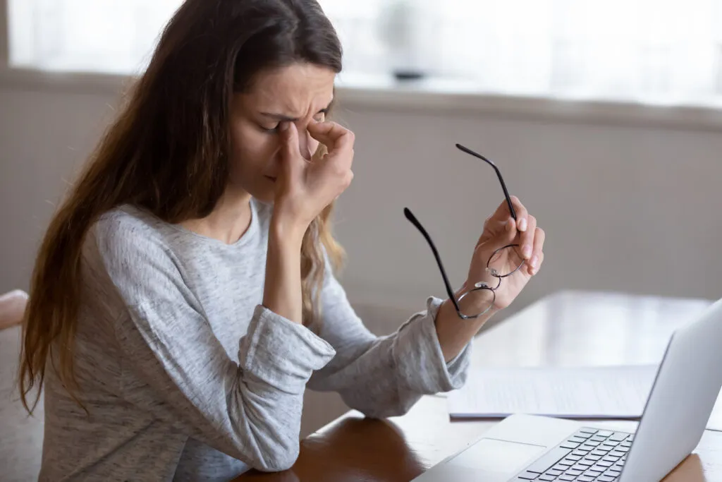 Frau reibt sich müde die Augen vor dem Laptop